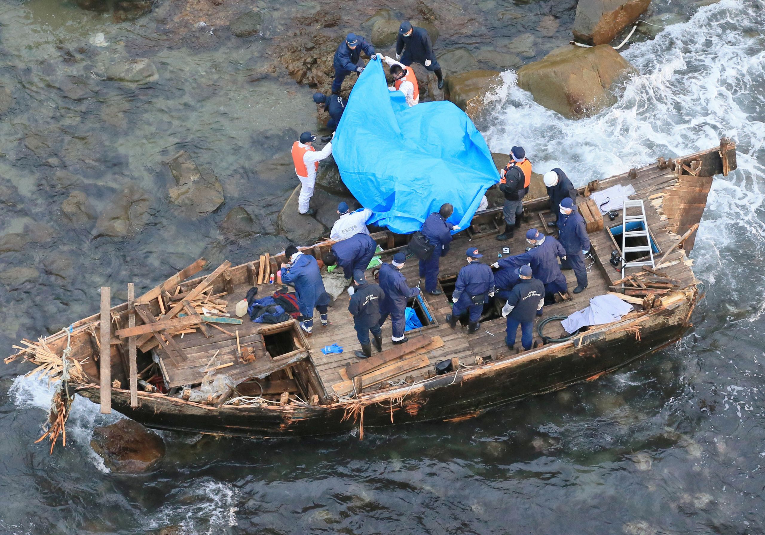 Police officers investigate a wooden boat marked with Hangul characters on Sado island, Japan, on  Nov. 28, 2012. 